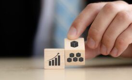 Businessman holds wooden cubes featuring business and graph icons, symbolizing lean process management strategies.