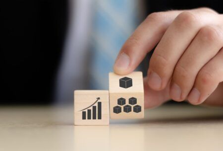 Businessman holds wooden cubes featuring business and graph icons, symbolizing lean process management strategies.