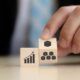 Businessman holds wooden cubes featuring business and graph icons, symbolizing lean process management strategies.