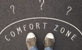 feet standing on road with question marks and comfort zone sign, symbolizing leaving the comfort zone