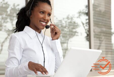 Smiling woman in headset on laptop, showing live chat etiquette.