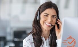 a smiling woman wearing a headset operates a computer, actively participating in outbound calling