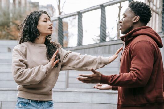 a man and woman engage in a heated discussion on the steps, highlighting the challenges of relationship building