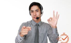 A man in a headset enthusiastically points at a screen, showcasing effective telephone techniques in action.