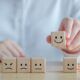 A person displays wooden blocks featuring smiley faces, highlighting a creative method for enhancing customer experience training