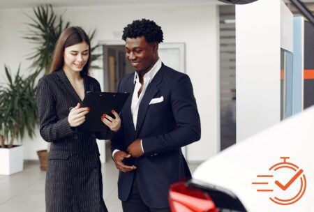 a man and woman at a car dealership, focused on a tablet, exploring options with a customer first approach