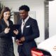 a man and woman at a car dealership, focused on a tablet, exploring options with a customer first approach