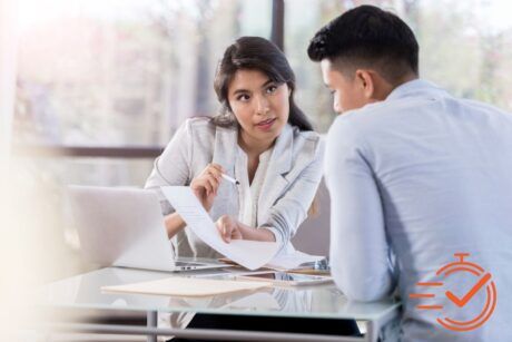 a female manager talking to a male employee at a table with a laptop, sharing insights and giving feedback as a manager