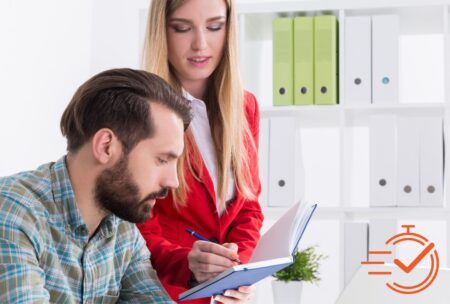 A man and woman collaborate on a notebook, sharing ideas and giving instructions to each other.