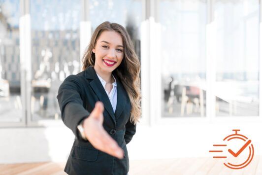 A confident woman in a business suit extends her hand, symbolizing leadership and new beginnings in the workplace.