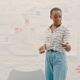 A woman stands confidently in front of a whiteboard, leading a presentation skills training session.