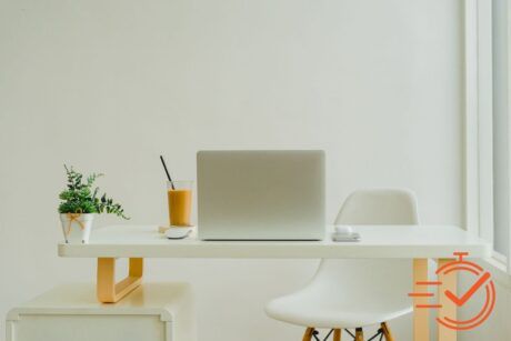 A cozy white desk setup featuring a laptop and a chair, perfect for working from home efficiently