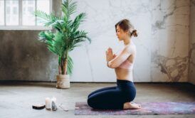 a woman sits in a yoga pose, a candle flickering nearby, representing peace in the face of anxiety and overwhelm