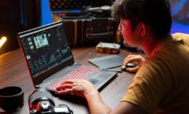 a man focused on his laptop, seated at a desk, engaged in a camtasia studio tutorial session