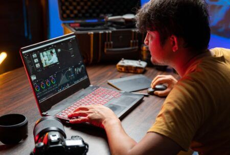 a man focused on his laptop, seated at a desk, engaged in a camtasia studio tutorial session