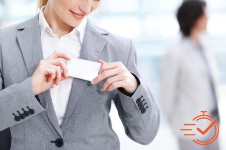 A woman in a sharp business suit confidently holds a business card, ready to make a good impression.