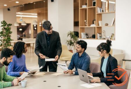 Team members gather at a table with laptops, embodying resilience and collaboration in a dynamic work environment.