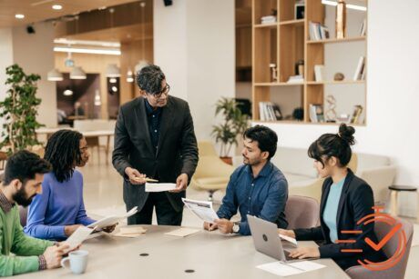 Team members gather at a table with laptops, embodying resilience and collaboration in a dynamic work environment.