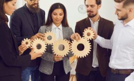 business professionals collaborating with wooden gears, symbolizing effective time management for managers