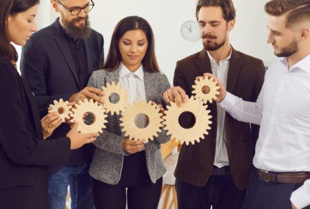 business professionals collaborating with wooden gears, symbolizing effective time management for managers