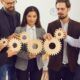 business professionals collaborating with wooden gears, symbolizing effective time management for managers