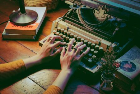 a person engaged in typing on an old typewriter, reflecting on their memoir writing course experience