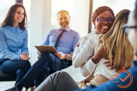 A heartfelt hug between two women in a meeting room emphasizes the essence of empathy training.