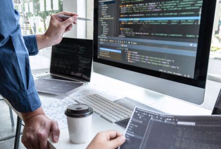 a man focused on his computer, utilizing a laptop and sipping coffee, immersed in learning javascript fundamentals