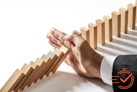 A suited individual pushes a domino block, symbolizing strategy in a crisis management course.