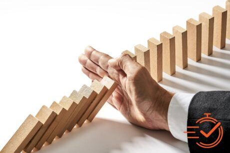 A suited individual pushes a domino block, symbolizing strategy in a crisis management course.