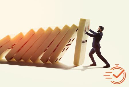 A man pushes a tower of dominos during a crisis management training session, illustrating the impact of decisions.