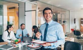 a smiling man in a business suit confidently holds a notepad, embodying professionalism and effective perception management