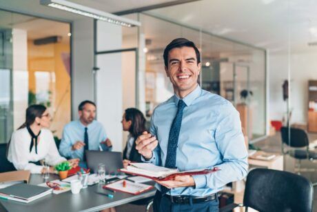 a smiling man in a business suit confidently holds a notepad, embodying professionalism and effective perception management