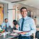 a smiling man in a business suit confidently holds a notepad, embodying professionalism and effective perception management