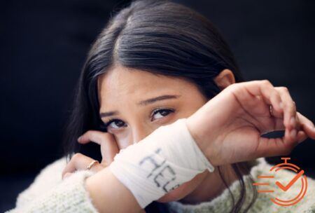 Person with long hair holds up her arm, revealing a white bandage with writing on it—a poignant reminder of struggles with self-harm and suicide thoughts.