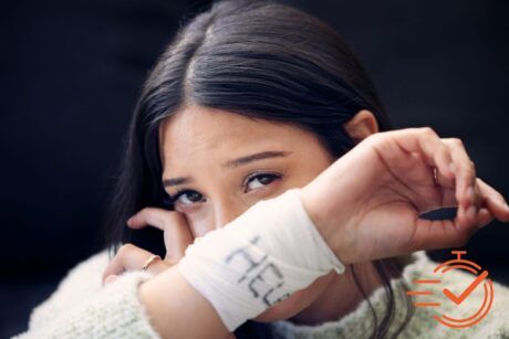 Person with long hair holds up her arm, revealing a white bandage with writing on it—a poignant reminder of struggles with self-harm and suicide thoughts.