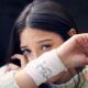 Person with long hair holds up her arm, revealing a white bandage with writing on it—a poignant reminder of struggles with self-harm and suicide thoughts.