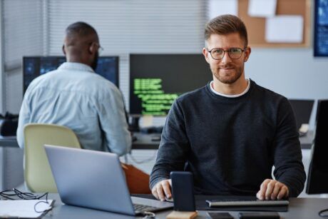 a man at a desk using a laptop and computer, focused on learning terraform for beginners