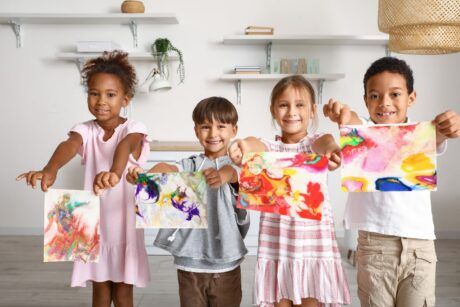 children proudly display their paintings in a room, showcasing their creativity through art therapy for children