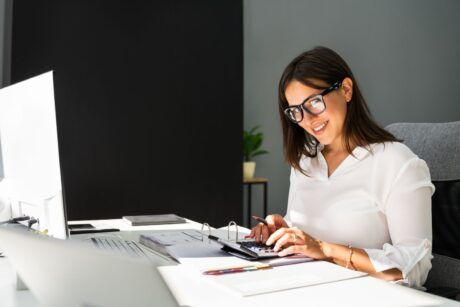 a woman in glasses is engaged in bank reconciliation while working on her computer