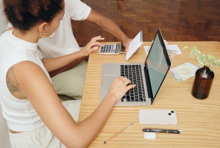 a man and woman discuss debt and credit while seated at a table with a laptop open between them