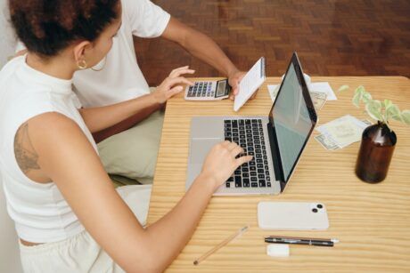 a man and woman discuss debt and credit while seated at a table with a laptop open between them